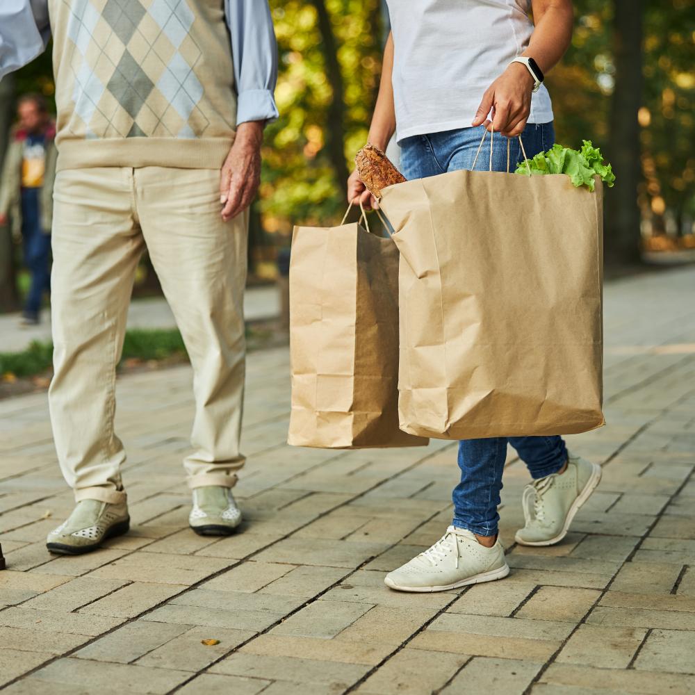 Frau hilft älteren Menschen beim Einkaufen